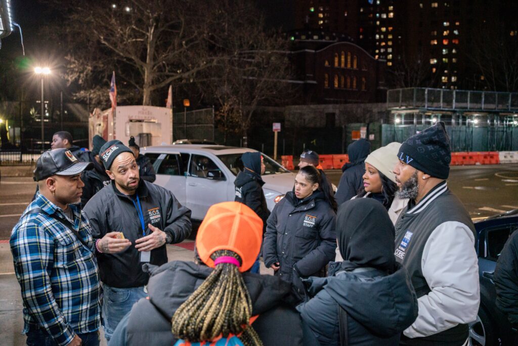 A group of people speaking with Cure Violence staff in a circle outside