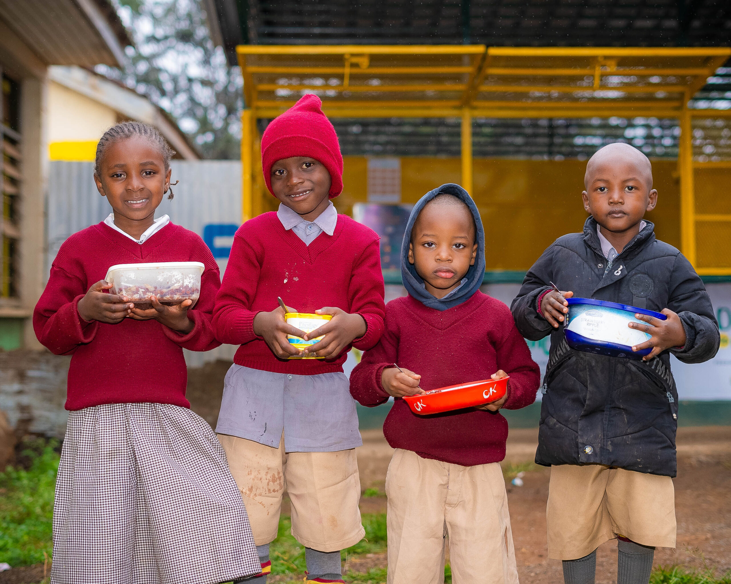 A group of children smiling and holding their lunches