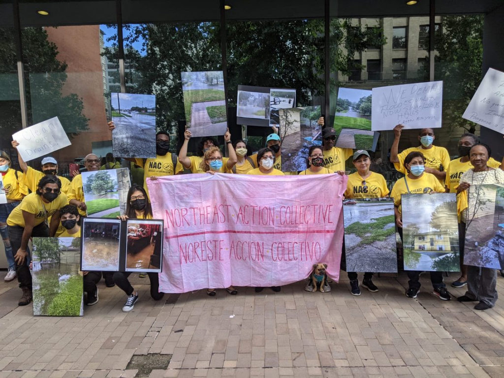 A group of people holding up photos of flooding damage and a banner that says ``Northeast Action Collective``